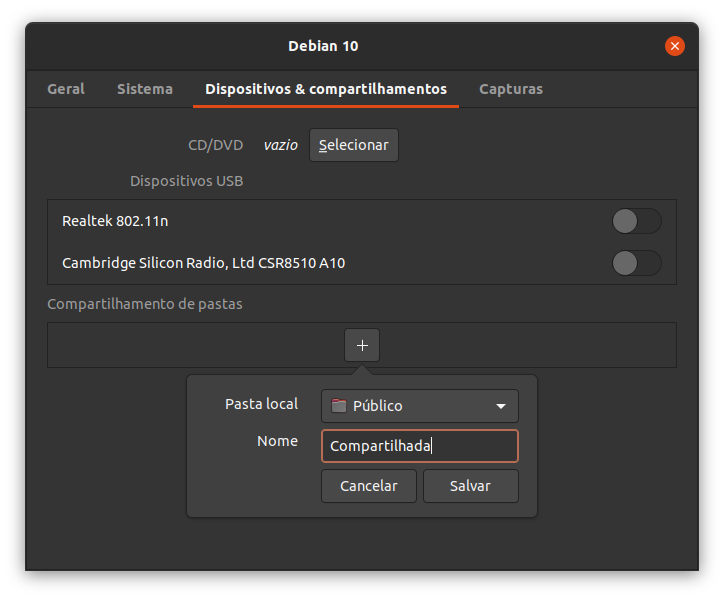 Exibindo a janela adicional do menu propriedades com as abas superiores Geral, Sistema, Dispositivos e compartilhamentos e Capturas. A aba Dispositivos e compartilhamentos está selecionada. Logo abaixo há um botão para selecionar uma imagem de CD/DVD. Logo abaixo é exibido um espaço em forma de lista para selecionar os dispositivos USB (dispositivo à esquerda e botão de checagem à direita) (há dois dispositivos disponíveis na imagem). Mais abaixo é exibido um botão com ícone de soma para adicionar compartilhamento de pasta. Esse último ícone possui um menu com os seguintes parâmetros na vertical: Um combo para selecionar a pasta, um campo de texto para dar o nome e dois botões na horizontal para cancelar e salvar (a partir da esquerda).